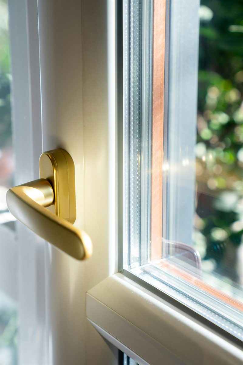 Détail d'une fenêtre PVC avec poignée dorée pour le confort acoustique